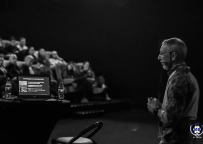 Intervenant sur scène pendant une conférence sur Cyno-Ops, en noir et blanc