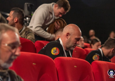Visiteur arborant le patch de la Brigade des Chiens de Police de Genève dans la salle de conférence